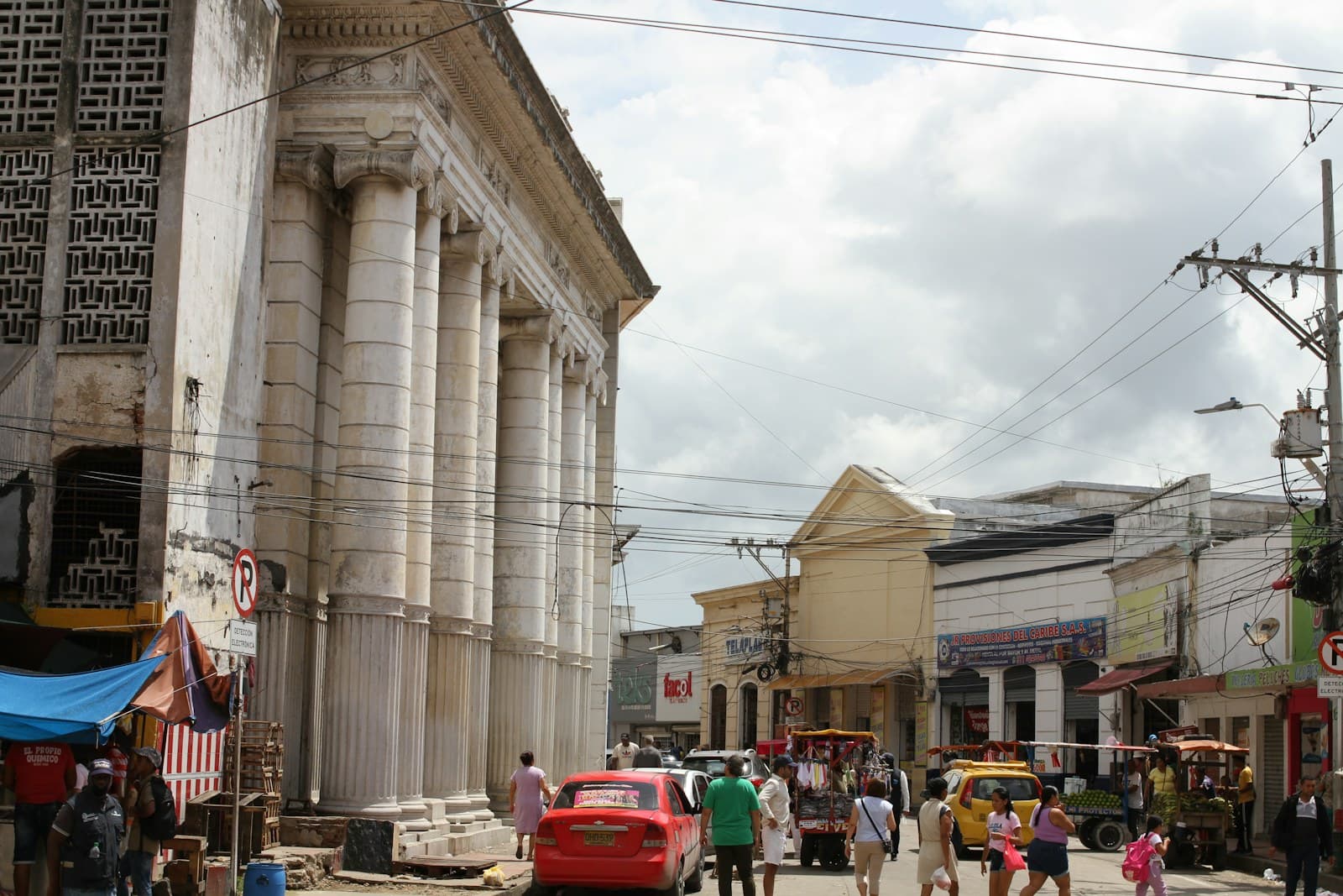Barranquilla: A group of people walking down a street next to tall buildings