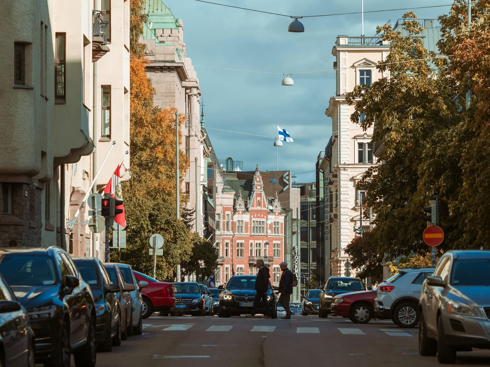 Finland: two person walking across street near parked cars