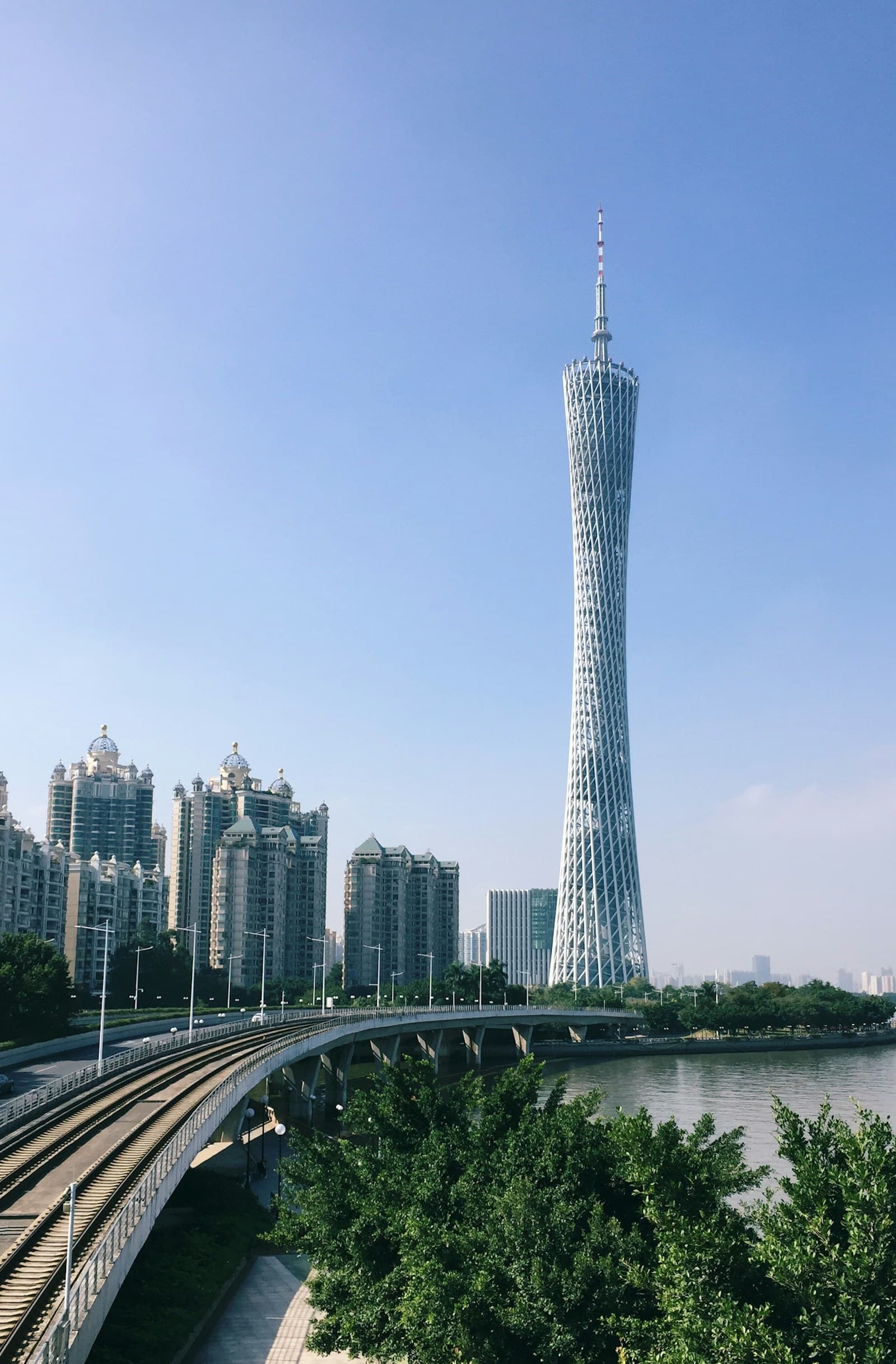 Guangzhou: a very tall tower towering over a city next to a river