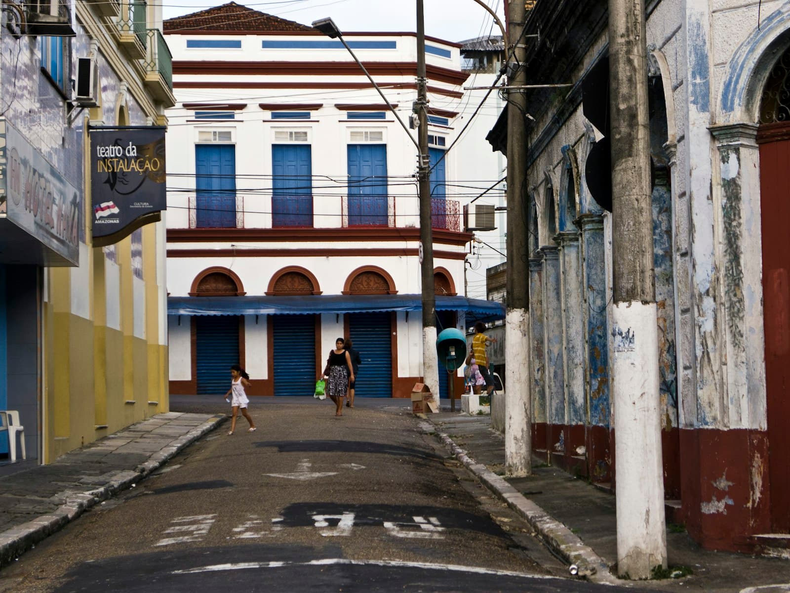 Manaus: a group of people walking down a street next to tall buildings