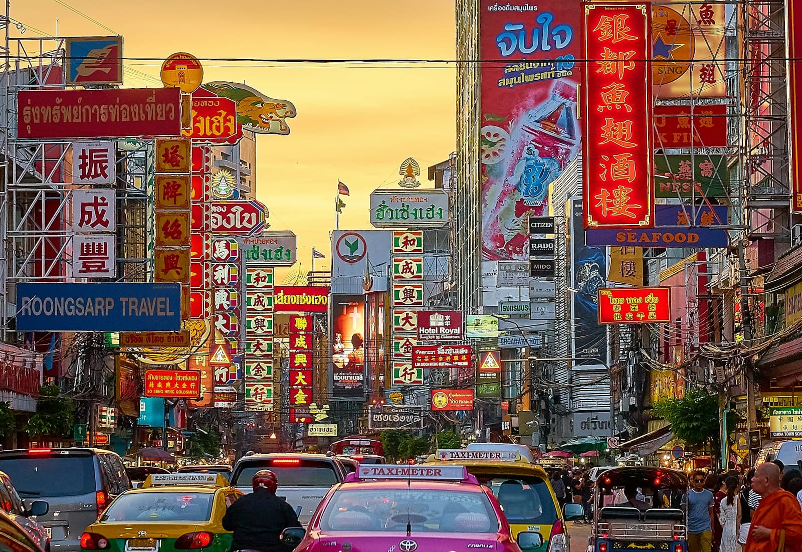 Bangkok: vehicles on street between buildings with Kanji script signage during golden hour